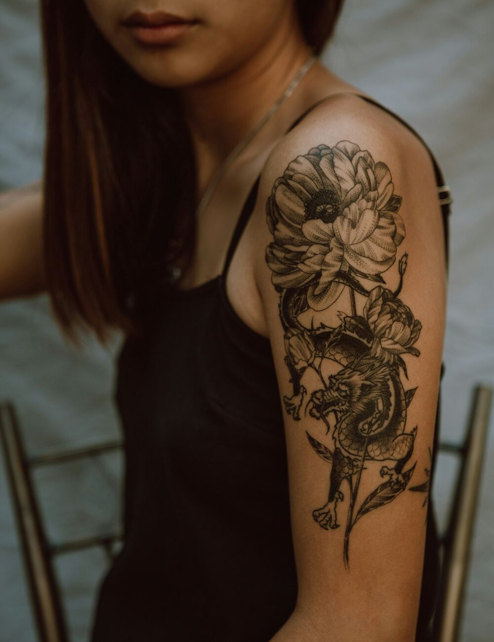 Black-and-grey floral and dragon upper-arm tattoo